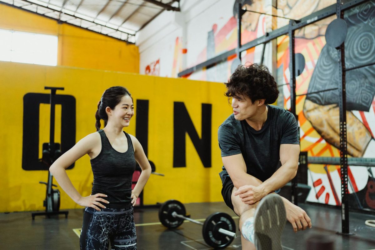Two people in sportswear interacting in a vibrant gym environment, showing fitness and camaraderie.