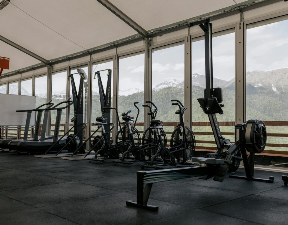 Spacious indoor gym featuring state-of-the-art equipment with scenic mountain views outside large windows.
