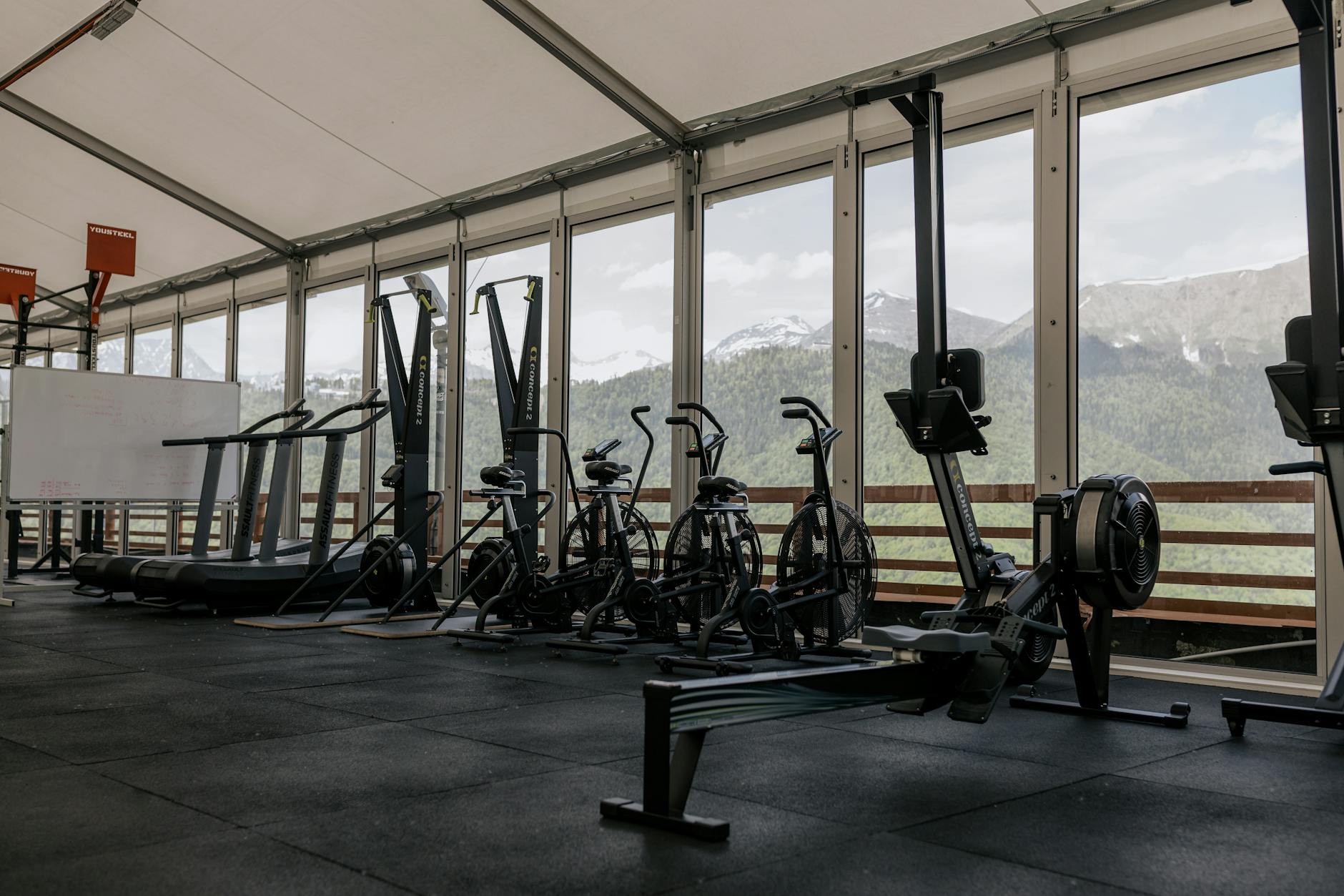 Spacious indoor gym featuring state-of-the-art equipment with scenic mountain views outside large windows.