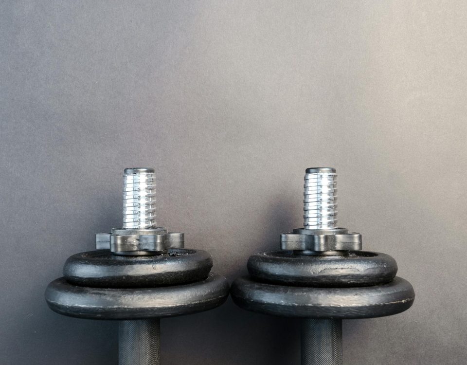 Close-up of two iron dumbbells on a gray background, perfect for strength training images.