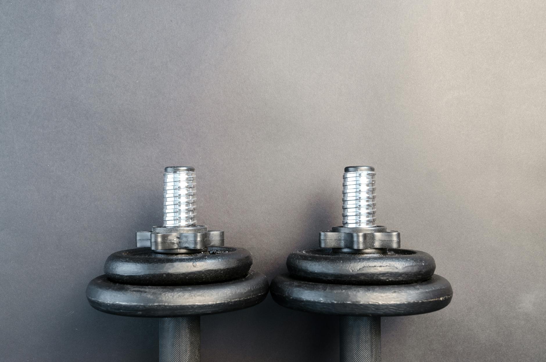 Close-up of two iron dumbbells on a gray background, perfect for strength training images.