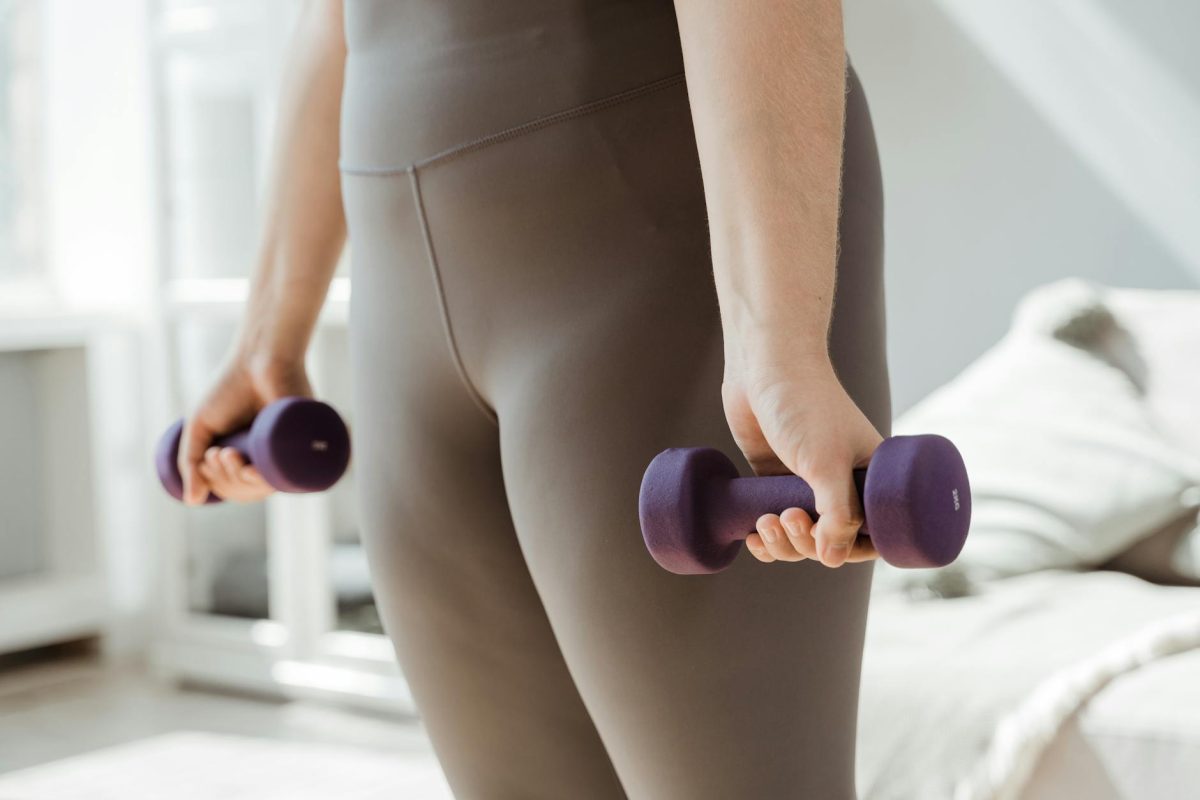 Close-up shot of a person holding purple dumbbells, symbolizing fitness and healthy living.