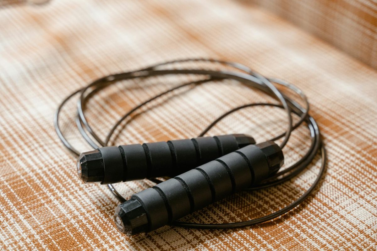 A black jump rope coiled on a patterned plaid surface, highlighting fitness equipment.
