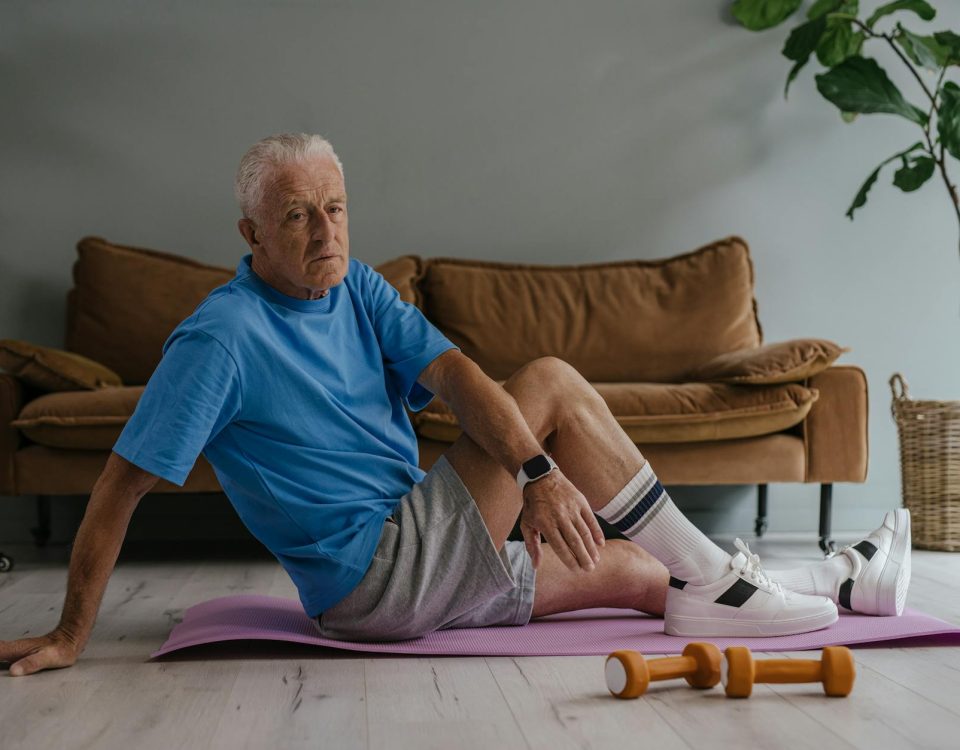 Elderly man enjoys a healthy lifestyle by exercising indoors on a yoga mat with weights.