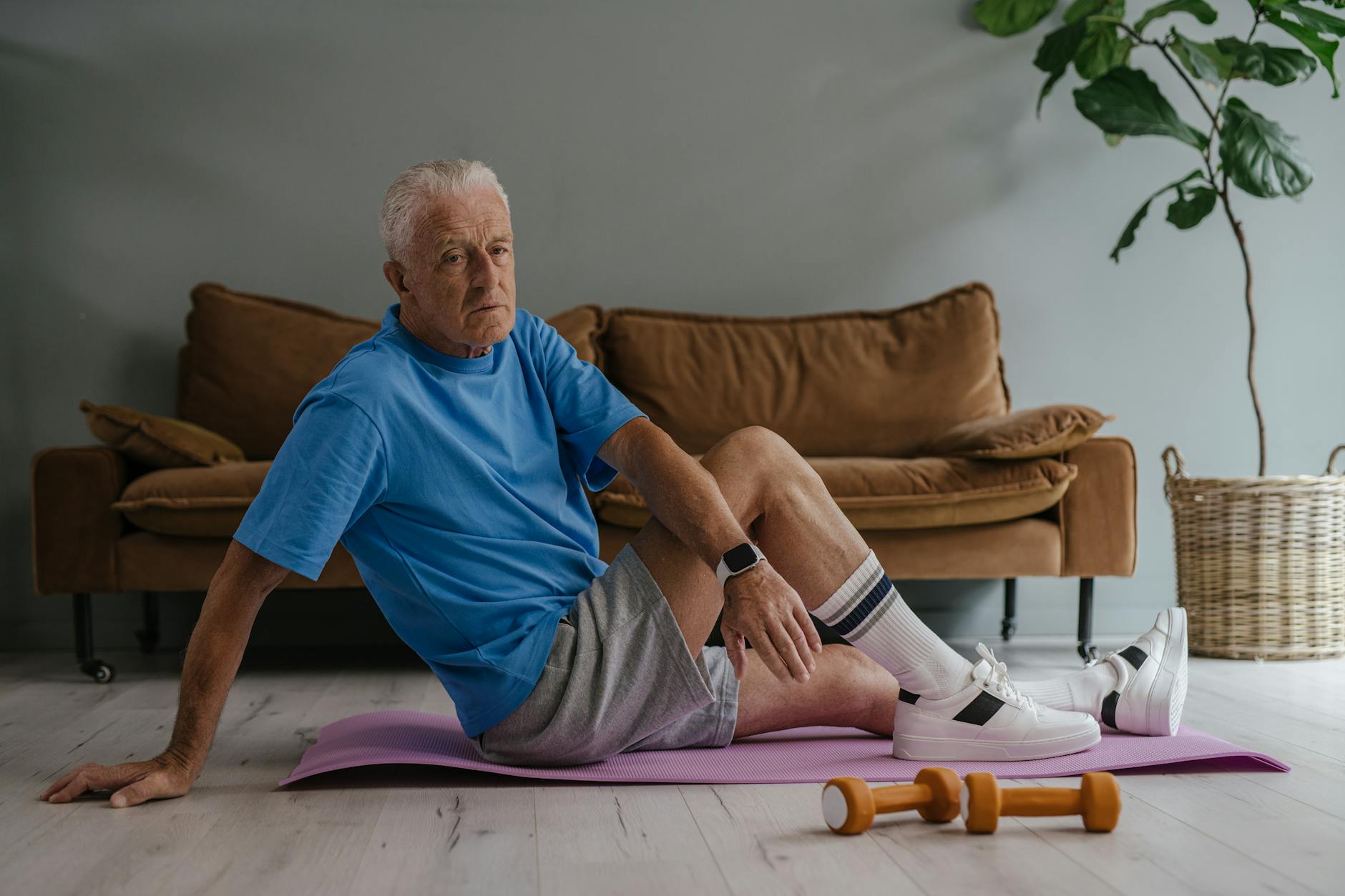 Elderly man enjoys a healthy lifestyle by exercising indoors on a yoga mat with weights.