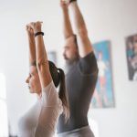 Elderly couple stretching together indoors for a healthy lifestyle routine.