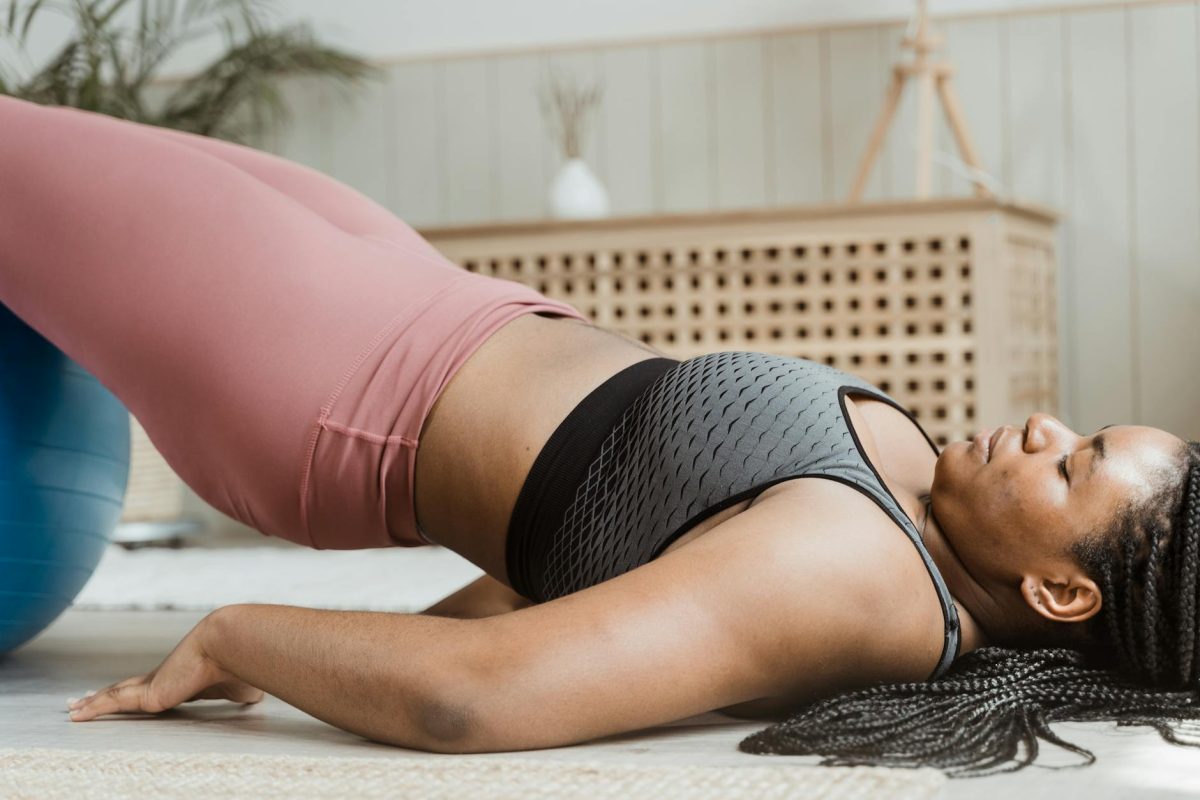 Young woman in activewear doing home workout with a fitness ball. Emphasizes body positivity and wellness.