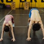 Two athletes stretching in a gym, focusing on flexibility and strength.