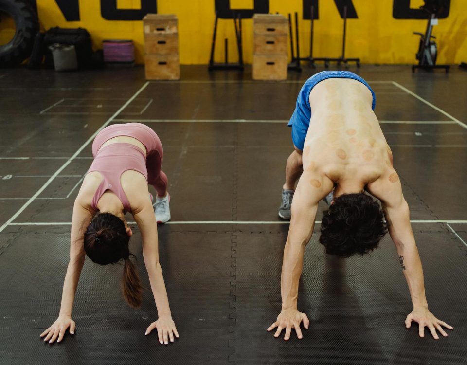 Two athletes stretching in a gym, focusing on flexibility and strength.