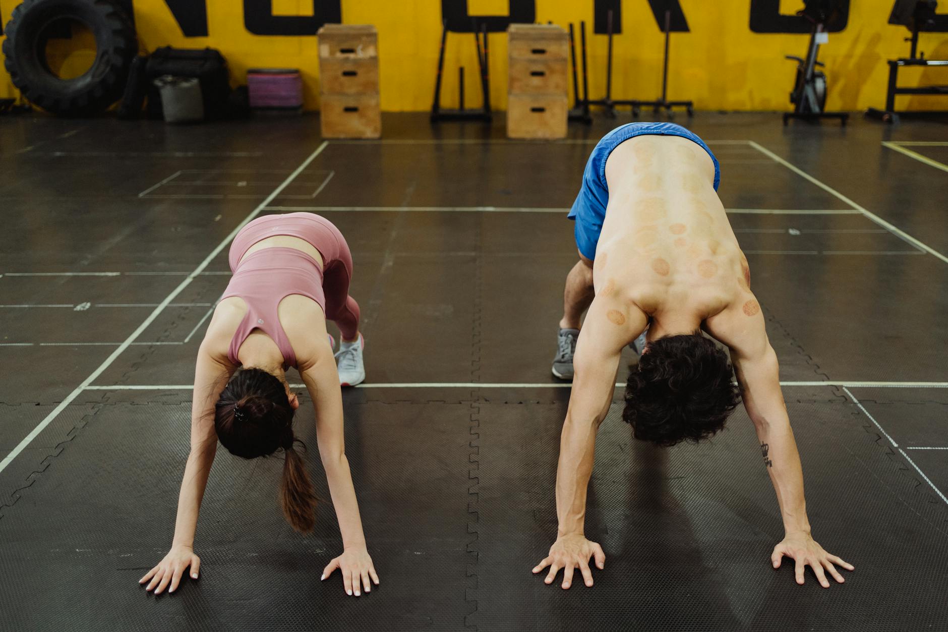 Two athletes stretching in a gym, focusing on flexibility and strength.