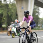 Woman wearing a mask and helmet cycling in Jakarta amidst pandemic.