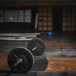 A lone barbell rests in an empty, dimly lit gym, emphasizing strength and solitude.