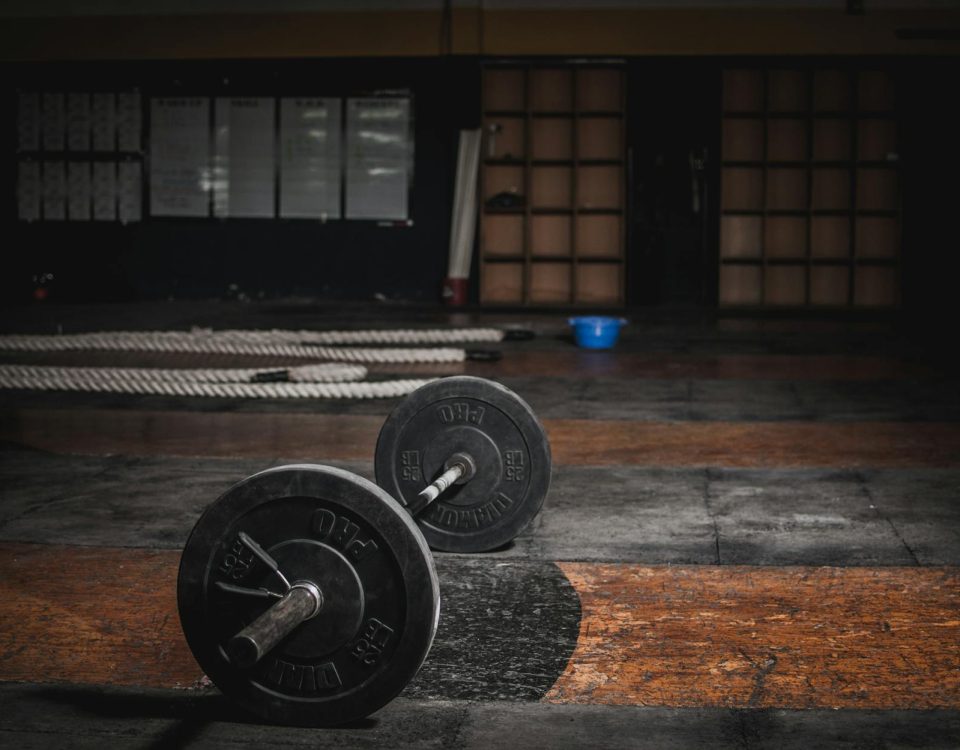 A lone barbell rests in an empty, dimly lit gym, emphasizing strength and solitude.