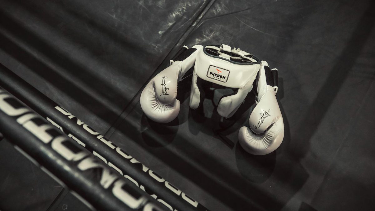 White boxing gloves and headgear on a boxing ring floor, emphasizing training and sport.
