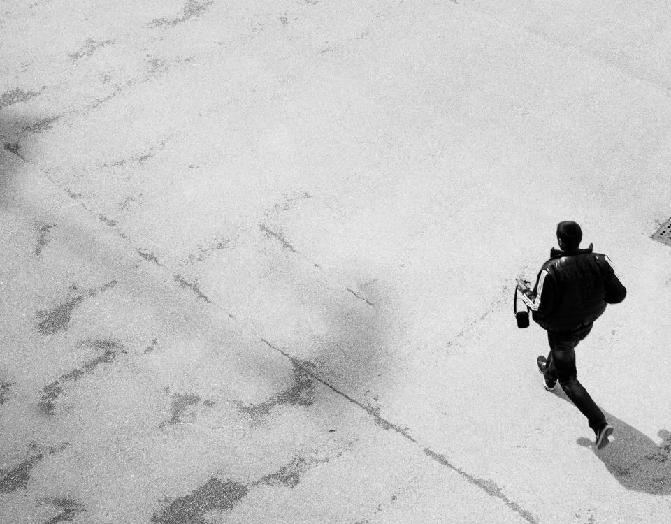 Black and white image of a man running on a paved street in Salzburg, Austria.