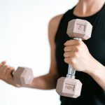 Close-up of a woman lifting dumbbells, focusing on a healthy lifestyle and fitness.
