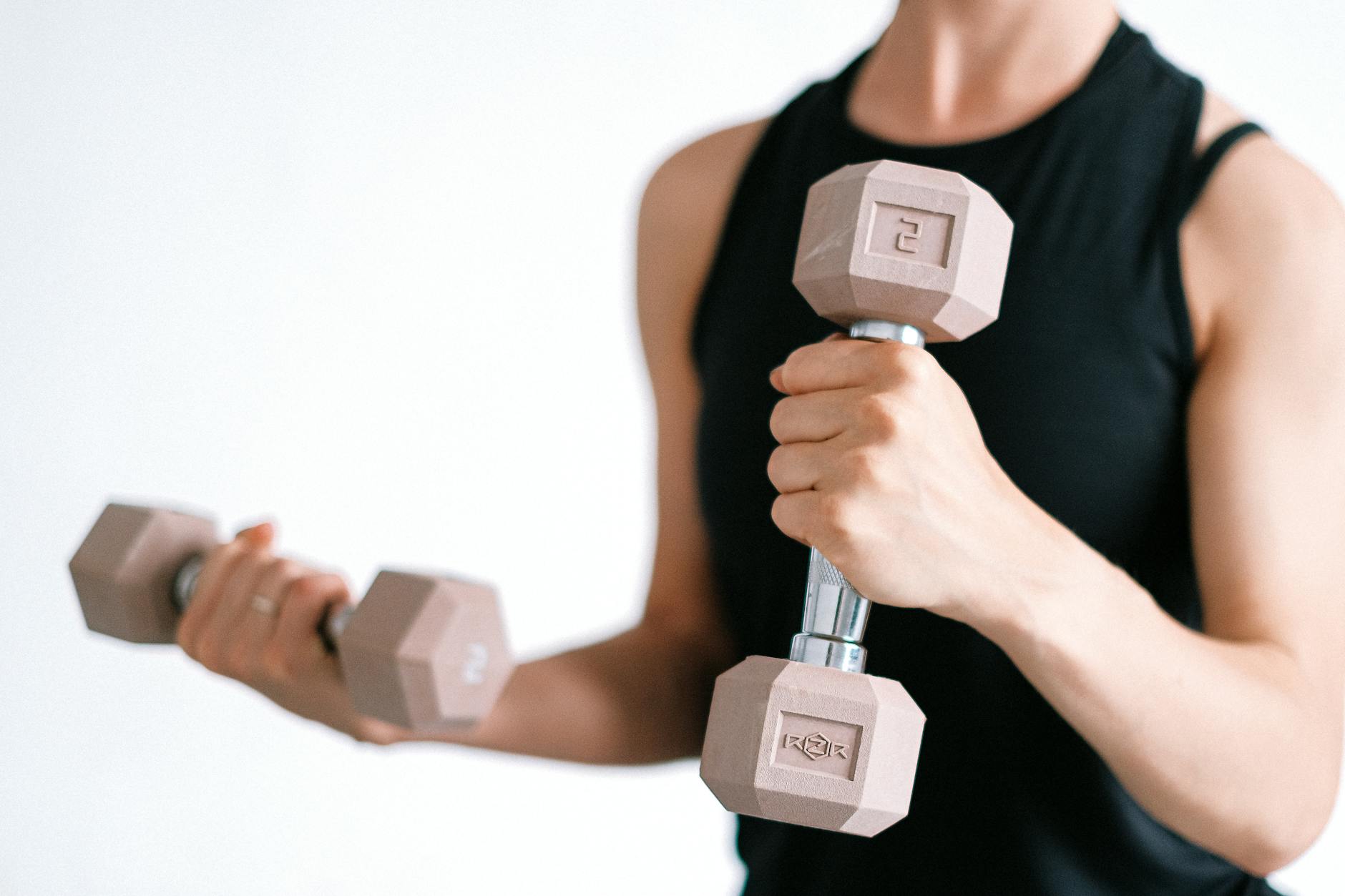 Close-up of a woman lifting dumbbells, focusing on a healthy lifestyle and fitness.