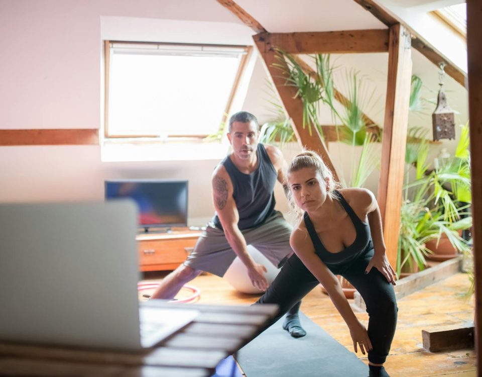 A man and woman working out at home using a laptop for guided exercises. Indoor active lifestyle.