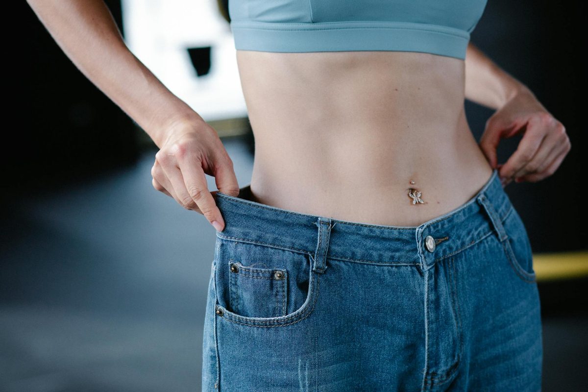 Close-up of woman pulling oversized jeans, illustrating weight loss.