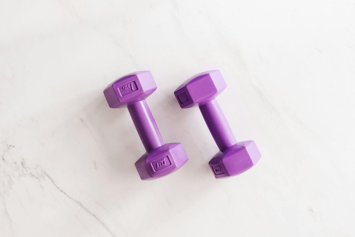 Overhead shot of two purple dumbbells on a white marble surface.
