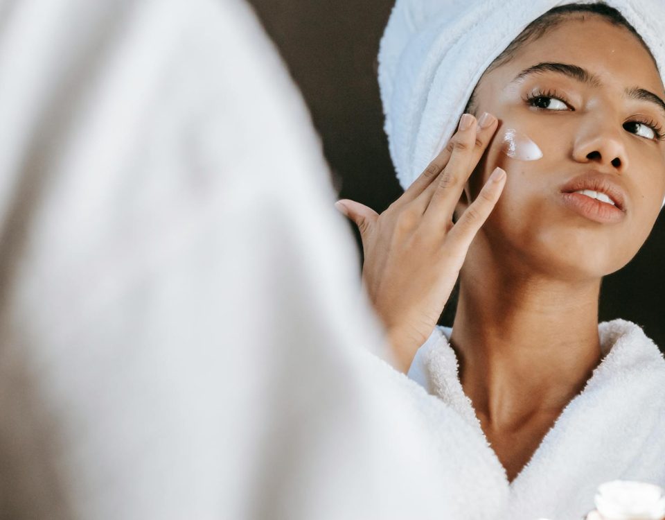 Woman in a bathrobe practices her skincare routine with moisturizing cream. Perfect for wellness themes.