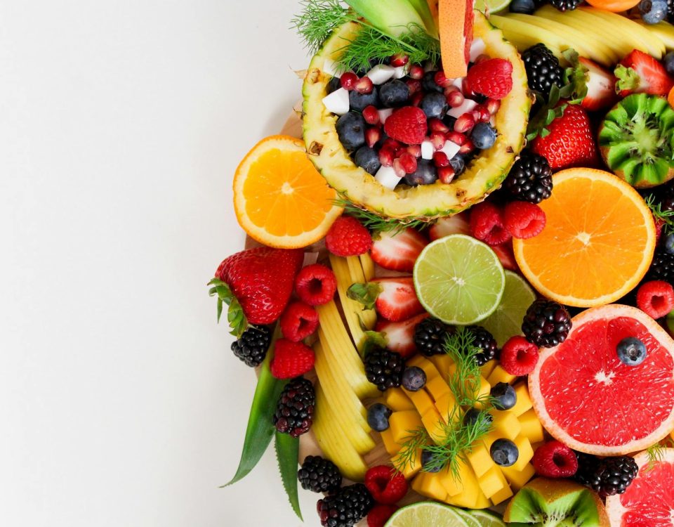 Colorful flat lay of assorted tropical fruits including pineapple, berries, and citrus.