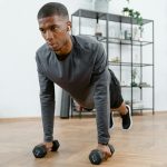 Man performing push-up exercises with dumbbells indoors. Fitness and healthy lifestyle concept.