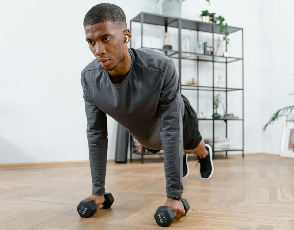 Man performing push-up exercises with dumbbells indoors. Fitness and healthy lifestyle concept.
