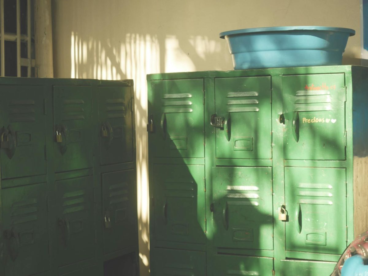 Sunlit vintage green lockers with padlocks in a retro room create a nostalgic scene.