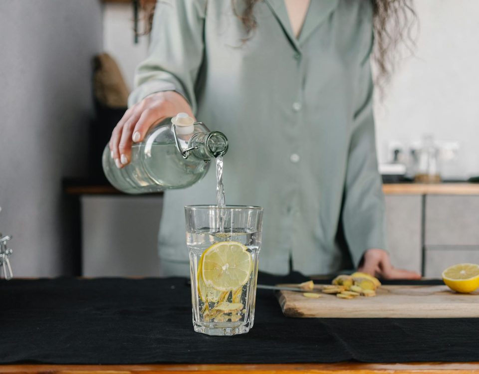 Woman pours water for lemon ginger infusion, promoting health and hydration.