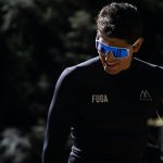Athlete in sleek gear and sunglasses enjoying a sunny outdoor environment.
