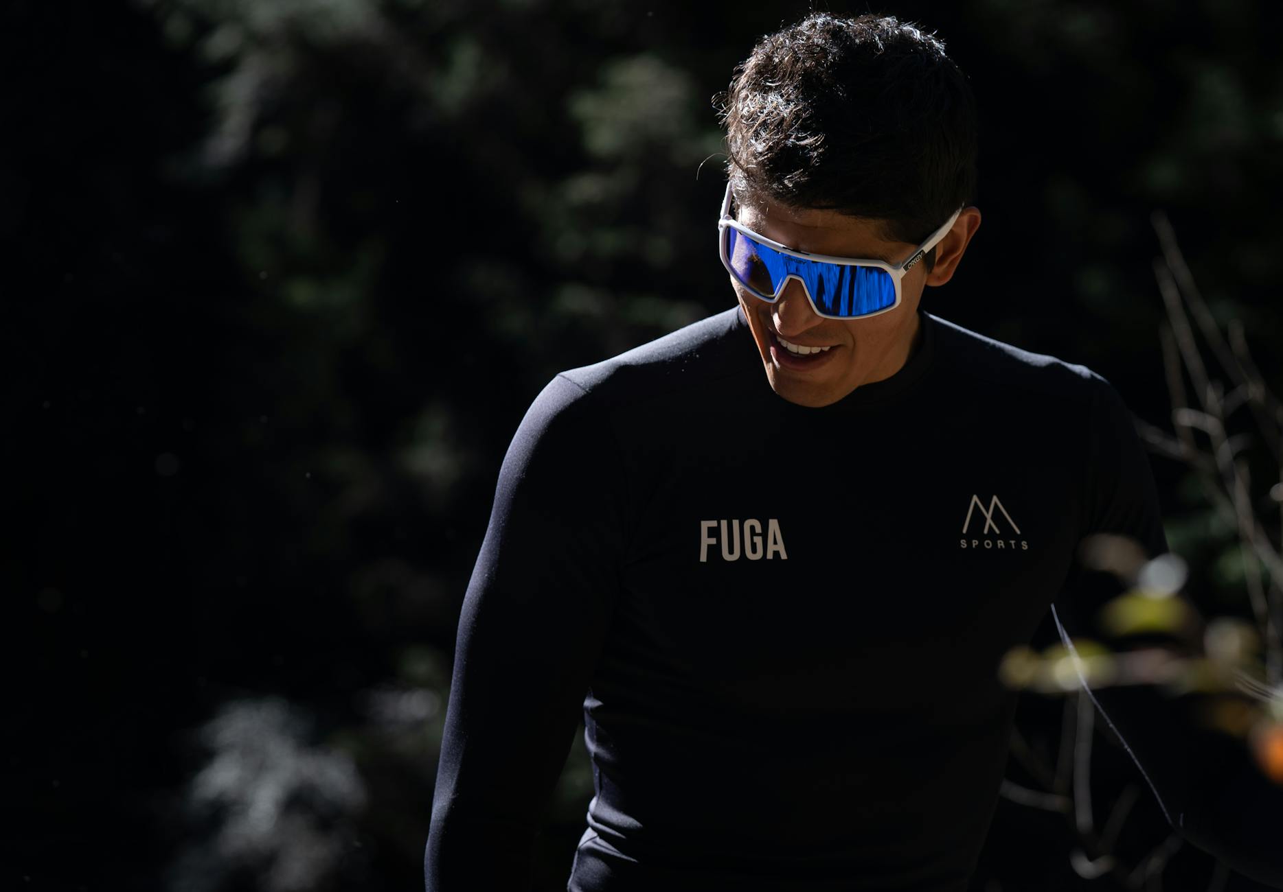 Athlete in sleek gear and sunglasses enjoying a sunny outdoor environment.