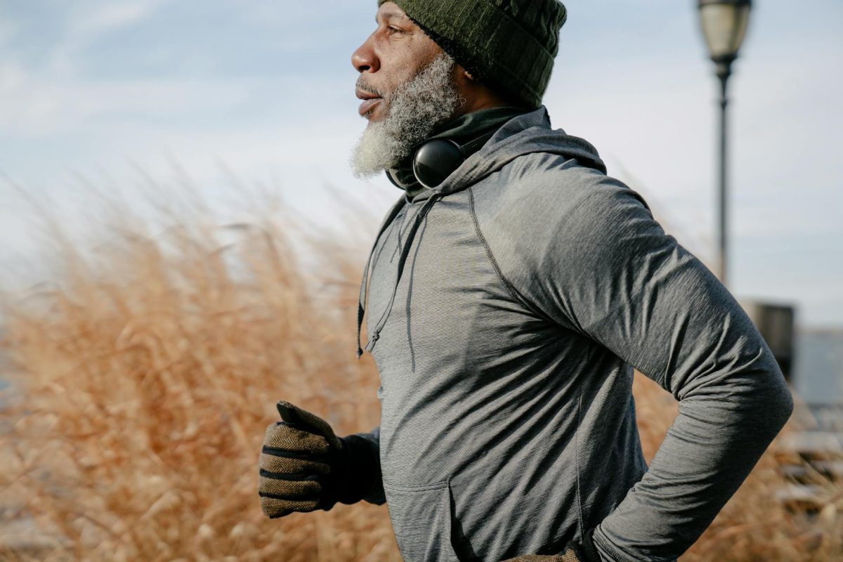 Senior African American man enjoying a run outdoors in warm autumn clothing.
