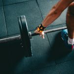 Close-up of a person lifting a barbell in an indoor gym, focusing on strength training.