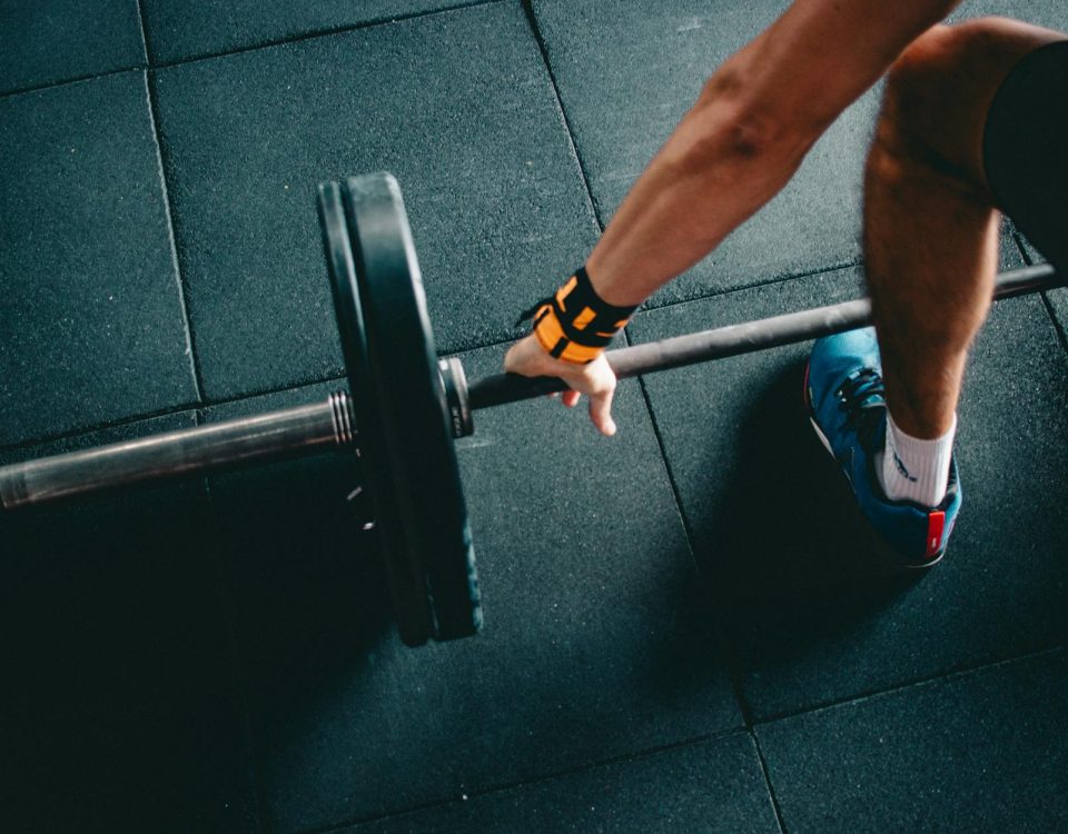 Close-up of a person lifting a barbell in an indoor gym, focusing on strength training.