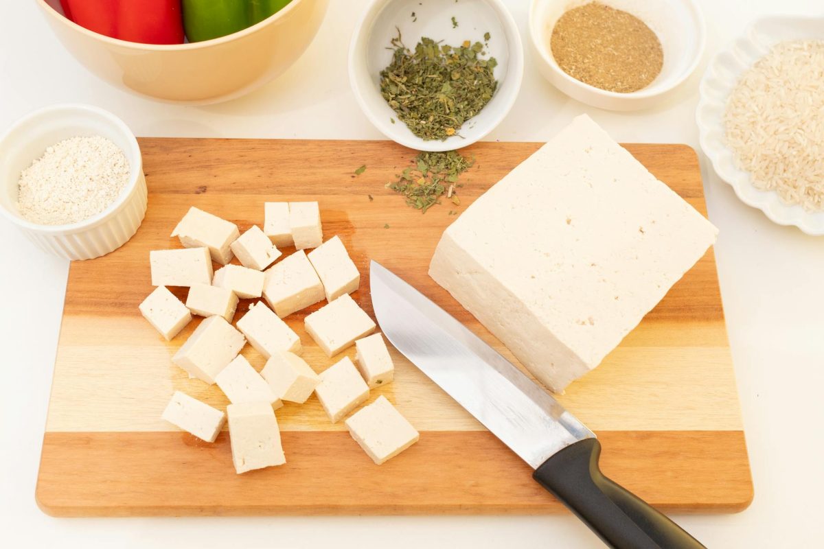 Sliced tofu on cutting board with herbs and spices, perfect for vegan meal ideas.