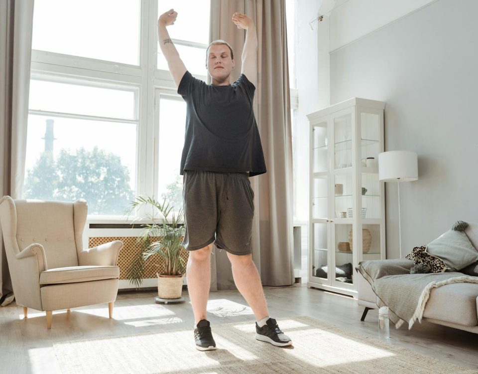 A young man enjoying a morning stretch in a bright, airy living room, embracing a healthy lifestyle.