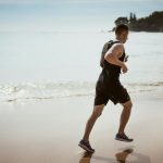Man running along the beach enjoying fitness and freedom by the ocean waves.