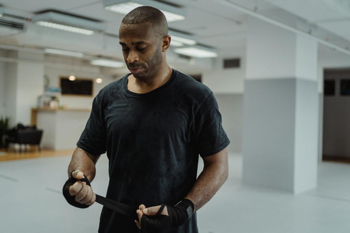 Male athlete wrapping hands with bandages in a modern indoor gym setting.