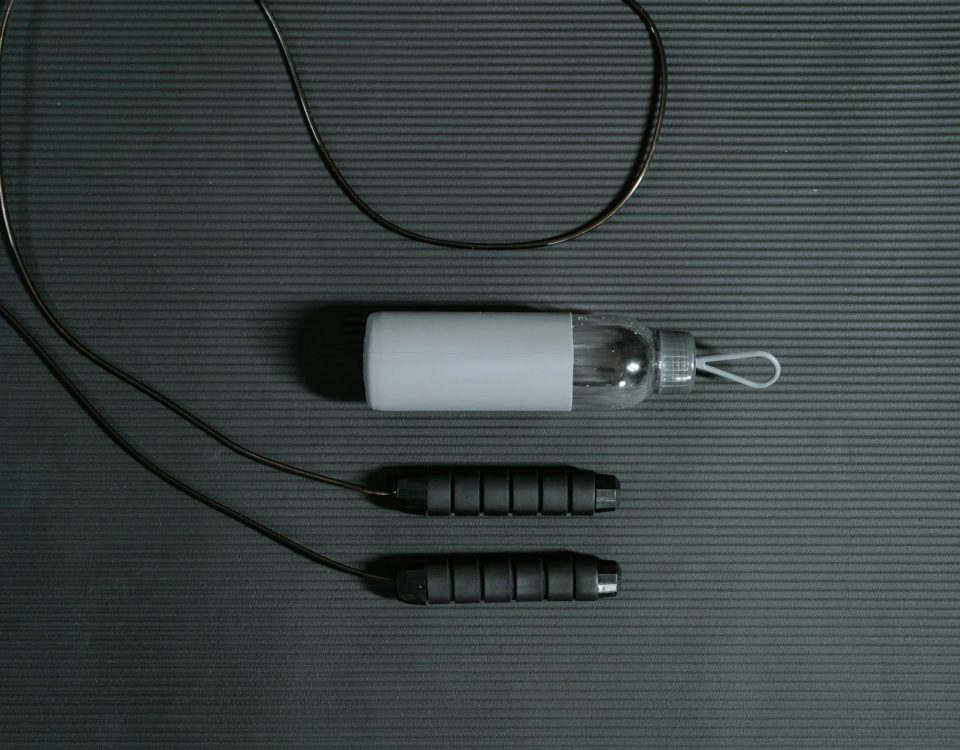 Flat lay of jump rope and water bottle on a yoga mat for fitness and hydration.