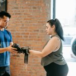 Fitness trainer helping a woman with boxing gloves in an urban gym.