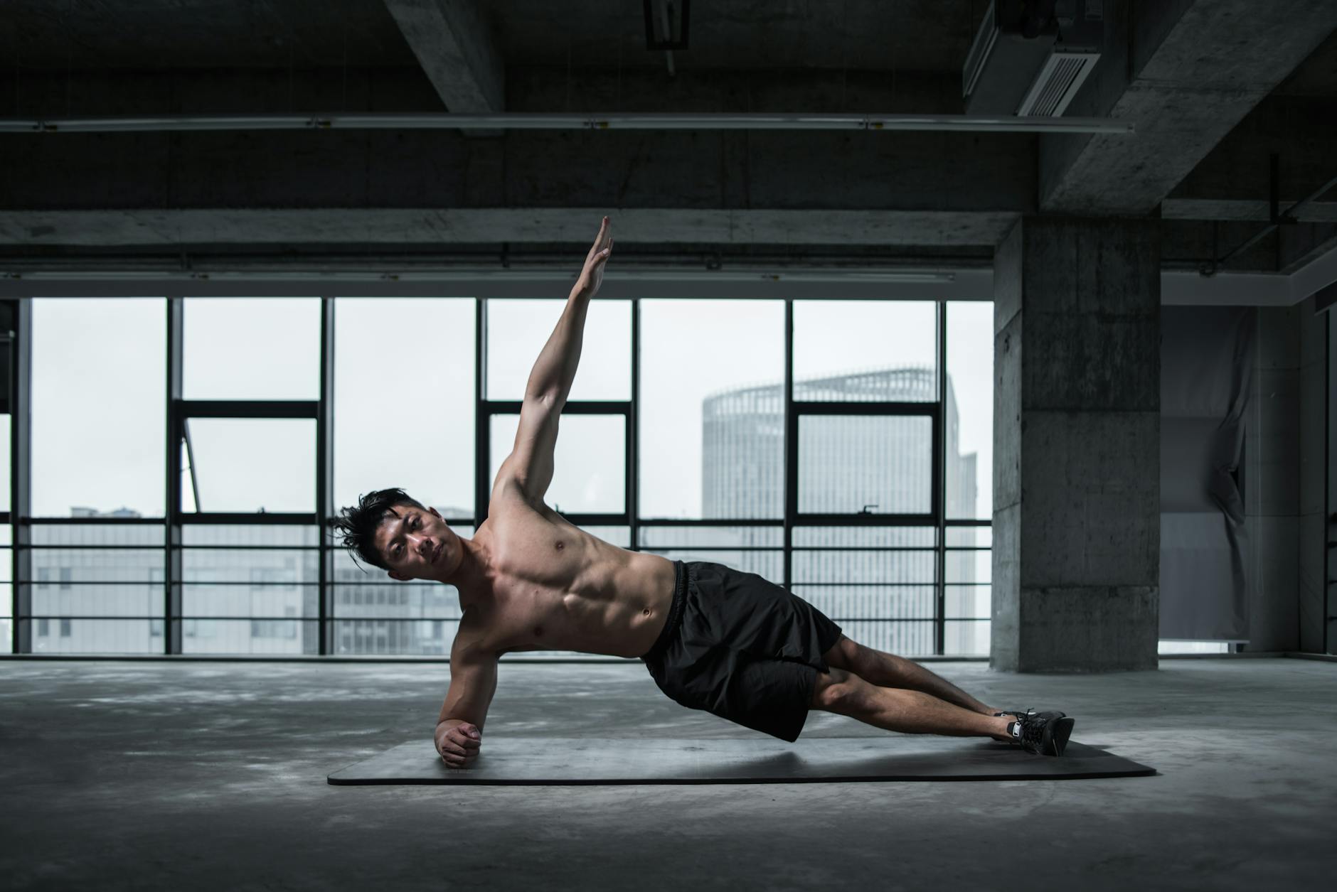 Fit man doing a side plank in an urban indoor gym, showcasing core strength and balance.