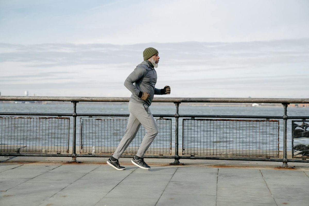 Elderly man running along waterfront, embracing a healthy lifestyle and exercise routine.