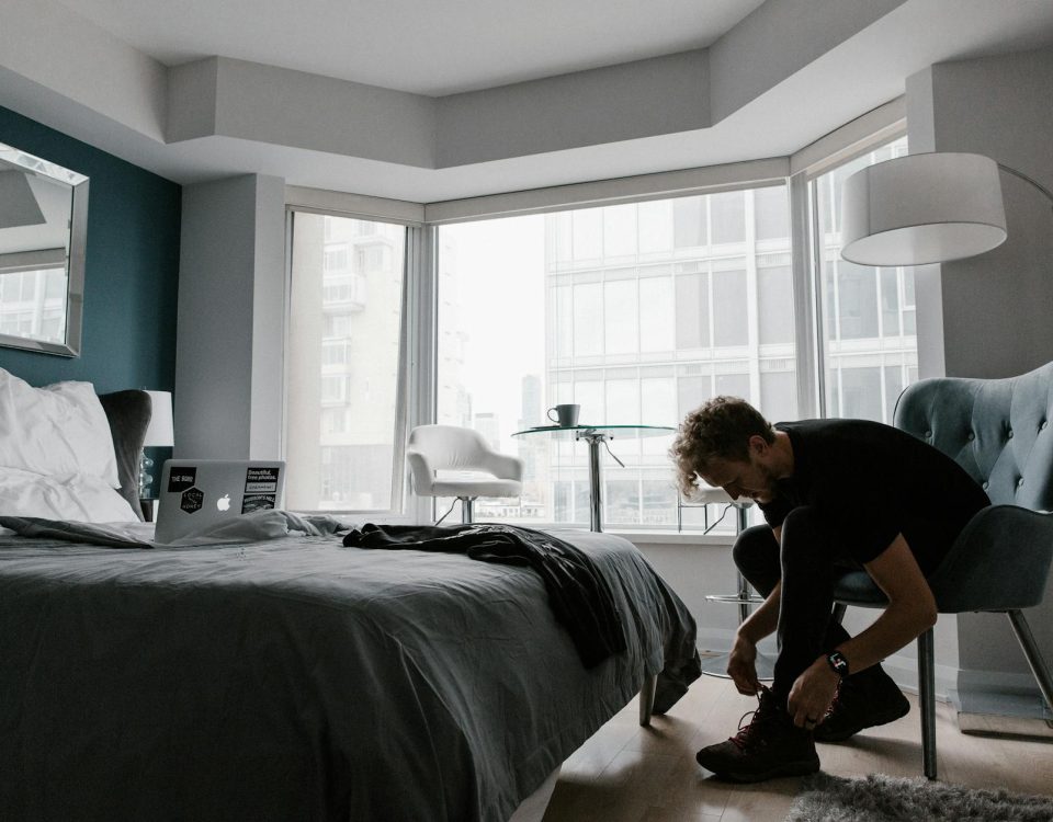 Contemporary hotel room with a man tying shoes in a bright Toronto setting.