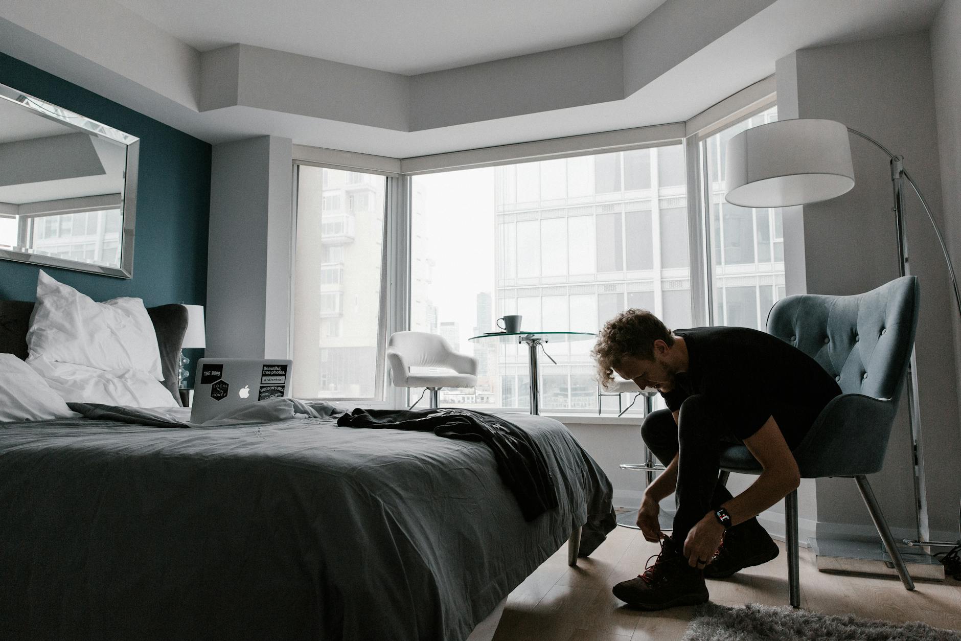 Contemporary hotel room with a man tying shoes in a bright Toronto setting.