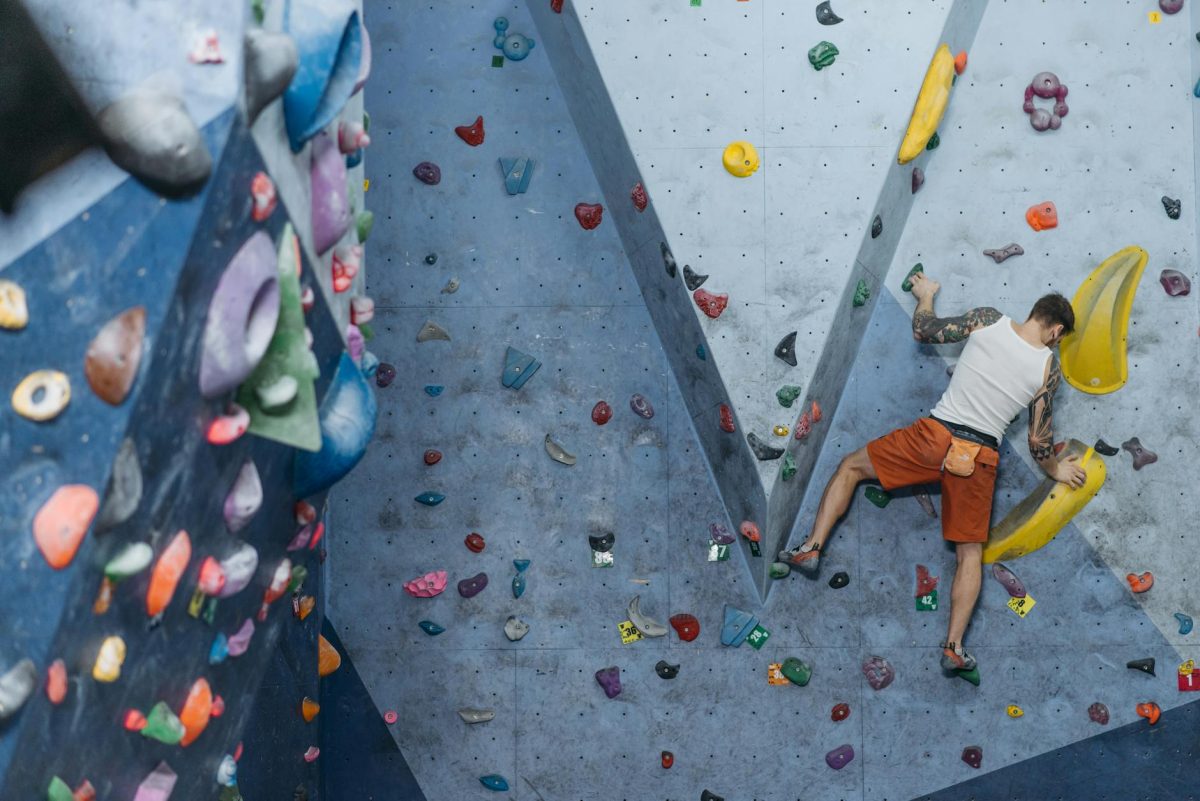 Man climbing a colorful indoor rock wall for fitness training.