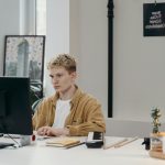 Young man concentrating on a computer screen at his modern workspace.