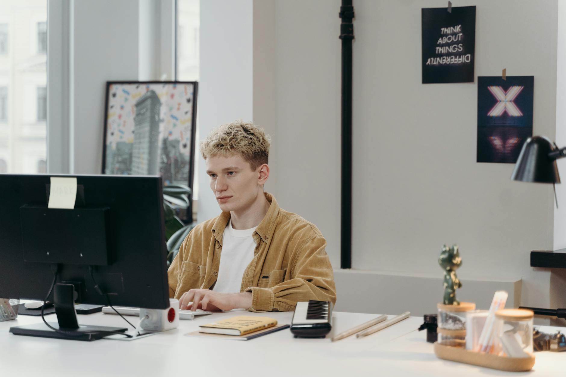 Young man concentrating on a computer screen at his modern workspace.
