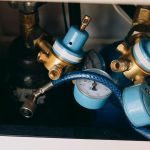 Detailed view of blue and brass gas pressure regulators with gauges and tubing in an industrial setting.