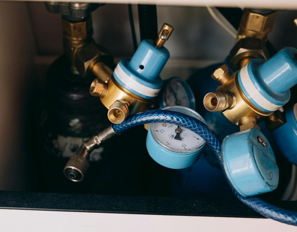 Detailed view of blue and brass gas pressure regulators with gauges and tubing in an industrial setting.
